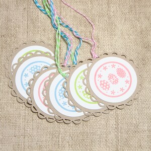 May include: Set of six round gift tags with scalloped edges. Each tag features a different pastel colored floral design with a white background. The tags are tied with twine.