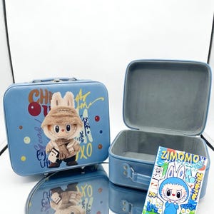 May include: Two light blue rectangular storage cases with rounded corners. One case is closed and features a plush rabbit figure wearing a tan hat and scarf. The other case is open, revealing a gray interior, with a ZIMOMO character card placed in front.