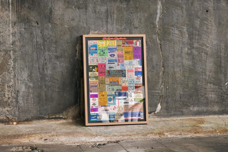 May include: A rectangular framed wall art piece featuring a collage of various colorful vintage tickets in shades of yellow, blue, pink, and green. The frame is light wood, and the top of the collage displays the red text St. Louis Cardinals.