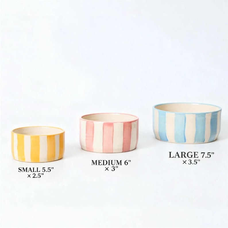 K&ouml;nnte beinhalten: Drei Keramikschalen mit vertikalen Streifen in Gelb, Rosa und Blau. Die kleine Schale ist 14 cm x 6,4 cm, die mittlere Schale ist 15,2 cm x 7,6 cm und die gro&szlig;e Schale ist 19 cm x 8,9 cm. Jede Schale hat einen cremefarbenen Innenraum.