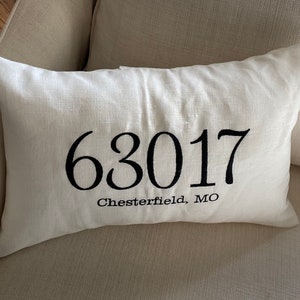 May include: A white linen pillow with black embroidery. The embroidery reads "63017 Chesterfield, MO".