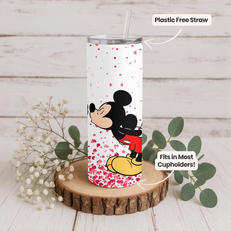 May include: A white tumbler with a silver lid and a plastic-free straw. The tumbler features a cartoon image of Mickey Mouse kissing, surrounded by red heart shapes. The text "Fits in Most Cupholders!" is also visible.