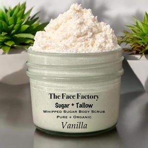 Può includere: Un barattolo di vetro trasparente pieno di uno scrub corpo allo zucchero montato bianco. Il barattolo ha il testo "The Face Factory Sugar + Tallow Whipped Sugar Body Scrub Pure + Organic Vanilla".