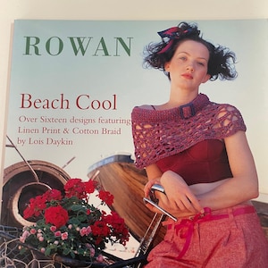 May include: A magazine cover with the title "ROWAN Beach Cool" featuring a woman wearing a crocheted shawl and shorts. The cover also displays text that reads "Over Sixteen designs featuring Linen Print & Cotton Braid by Lois Daykin". A bicycle and flowers are in the background.