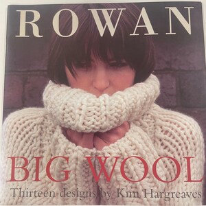 May include: A book cover featuring the word "ROWAN" in white capital letters above a woman wearing a cream-colored, chunky knit sweater. The words "BIG WOOL" are in red capital letters, with "Thirteen designs by Kim Hargreaves" below.