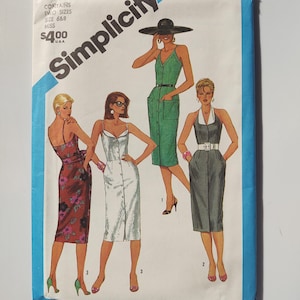 May include: Simplicity sewing pattern envelope with illustrations of four dresses. The envelope is white with blue trim and features the text "Simplicity" and the number "6453". The dresses are in different colours and styles, including a floral print and a button-down design.