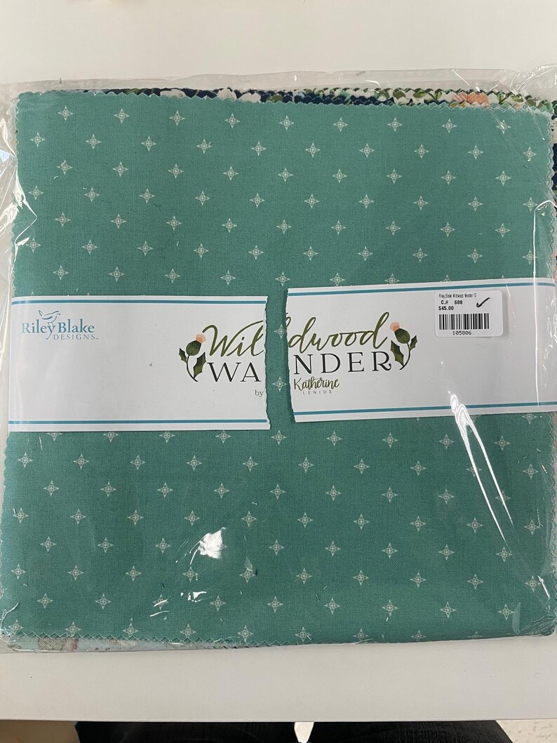 May include: A package of fabric squares in various patterns and colors. The dominant fabric is teal with a white geometric design. The package is labeled "Wildwood Wander" by Katherine Lenius and "Riley Blake Designs."