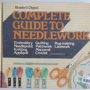 May include: A vintage "Reader's Digest Complete Guide to Needlework" book with a blue and orange title. The image includes embroidery floss, scissors, a crochet hook, and an embroidery hoop, showcasing various needlework techniques.