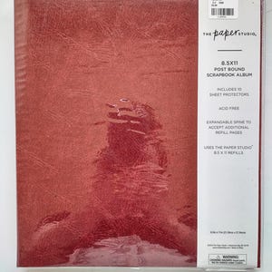 May include: A red 8.5x11 post bound scrapbook album by The Paper Studio. The cover has a textured finish. The packaging includes 10 sheet protectors, an expandable spine for refill pages, and states it is acid free. It uses 8.5x11 refills.