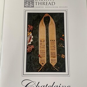 May include: A package for a needlework design kit. The kit features a beige and brown cross-stitch pattern with the text "Chatelaine and Scissors Keeper". The package also includes the text "The Drawn Thread" and "Charted Needlework Designs".