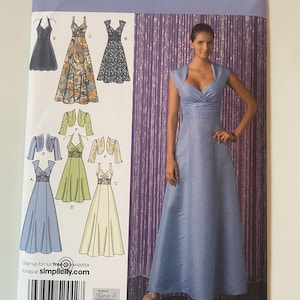 May include: A Simplicity 2442 sewing pattern envelope featuring illustrations of various dress styles with optional bolero jackets. The cover displays a long, light blue sleeveless gown with a V-neckline and a ruched waist, alongside technical sketches.