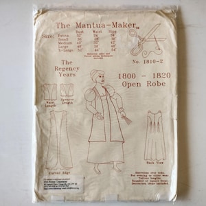 May include: A beige paper sewing pattern envelope titled The Mantua-Maker No. 1810-2 for an 1800-1820 open robe. The front features a line drawing of a person wearing the robe, size charts, a pair of scissors icon, and text detailing garment views.