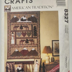May include: A McCall's Crafts pattern titled "American Tradition" featuring a quilt design with snow-covered mountains, a snowman, and heart and tree motifs. The pattern includes the number 8327.
