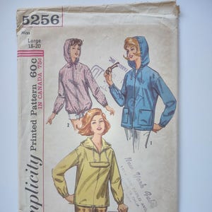Op de afbeelding: Vintage Simplicity naaipatroon 5256 met illustraties van jassen met capuchon. Het patroon is voor maten Large 18-20. Het patroon is gedrukt en bevat de tekst "New York Fabric".