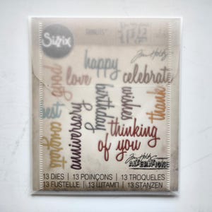 以下が含まれることがあります： 透明なプラスチック製のスリーブに入った13個のSizzix Alterationsカッティングダイセット。happy、love、celebrate、birthday、wishes、thank、best、congrats、anniversary、thinking of youという単語が、さまざまな筆記体フォントでデザインされています。