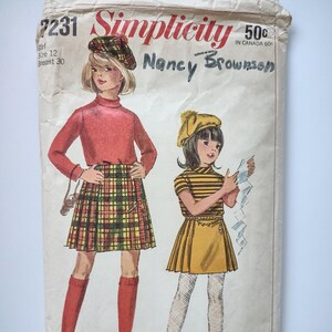 Può includere: Modello di cucito Simplicity vintage con illustrazioni di due ragazze in abiti coordinati. Una indossa un top rosso e una gonna a quadri, l'altra un vestito giallo con un top a righe. Il modello è etichettato "Nancy Brownson".