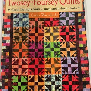 May include: A book titled "Twosey-Foursey Quilts" by Cathy Wierzbicki. The cover displays a vibrant quilt design with geometric patterns in orange, red, green, and purple. The book's subtitle reads "Great Designs from 2-Inch and 4-Inch Units."