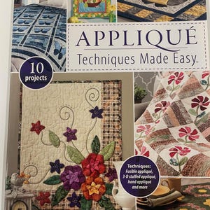 May include: A book cover titled "APPLIQUE Techniques Made Easy" by Annie's Quilting. The cover features images of quilts with floral and owl designs. The book includes 10 projects and various applique techniques.