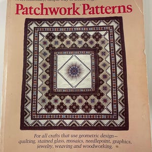 Könnte beinhalten: Ein Buch mit dem Titel "Patchwork Patterns" mit einem detaillierten Steppmuster auf dem Einband. Der Einband enthält den Text "A revolutionary, simple way to create original and traditional." Das Buch ist für Handwerke mit geometrischem Design.