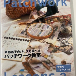 May include: A book titled "Patchwork" with the text "Lessons 2" in blue. The cover features a woven basket, a sewing machine, and an embroidery hoop with fabric. Japanese text is also visible.