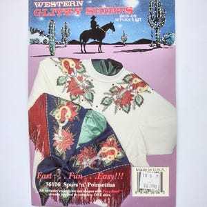 May include: A Christmas Western Glitzy Shirts iron-on applique kit package featuring a white shirt decorated with red poinsettias and gold spurs. The packaging displays a desert scene with a cowboy on horseback and includes the text 36106 Spurs 'n' Poinsettias.