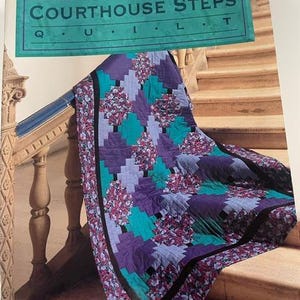 May include: A colorful quilt with a Courthouse Steps pattern, featuring shades of purple, teal, and floral accents. The quilt is draped over a wooden railing, with the book "Courthouse Steps Quilt" visible in the image.
