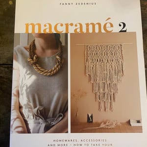 May include: A softcover book titled Macramé 2 by Fanny Zedenius. The cover features a white background with the title in orange and black text. It displays two photographs: one of a person wearing a thick rope necklace and one of a wall hanging.