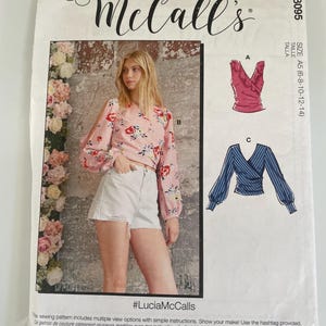 May include: A McCall's M8095 sewing pattern envelope featuring a pink floral long-sleeve top with shoulder cutouts and white denim shorts. The package includes illustrations for two additional top designs, labelled A and C, in size A5.
