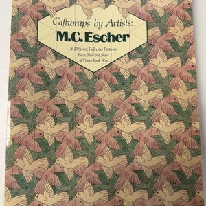 Puede incluir: Un libro de tapa blanda titulado Giftwraps by Artists: M.C. Escher con un patrón repetitivo de aves entrelazadas en color crema y verde. El texto de la portada dice 16 Different, Full-color Patterns. Each Tear-out Sheet 4 Times Book Size.