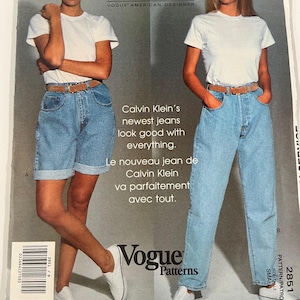 May include: An advertisement for Calvin Klein Jeans from Vogue Patterns. The image shows two models in white t-shirts, light-wash denim jeans, and white trainers. The text reads "Calvin Klein's newest jeans look good with everything."