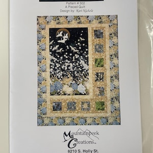 May include: A quilt pattern named "Sidelights" by Kari Nichols, featuring a pieced design. The quilt design showcases a night scene with cranes, flowers, and a full moon. The pattern includes the Mountainpeek Creations logo and contact details.