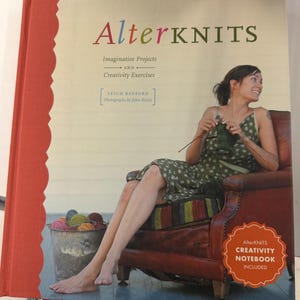 May include: A hardback book titled AlterKNITS: Imaginative Projects and Creativity Exercises by Leigh Radford. The cover features a person knitting in a leather chair, a bucket of yarn, and a badge stating Creativity Notebook Included.