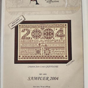 Peut inclure: Kit de point de croix "SAMPLER 2004" avec le texte "Anagram diffusion". Le kit comprend un motif avec les chiffres 2004, l'alphabet et d'autres éléments décoratifs. Le lin mesure 70 cm x 55 cm.