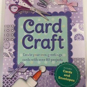 Może przedstawiać: Zestaw rzemieślniczy zatytułowany "Card Craft" z fioletowo-zielonym wzorem. Zestaw zawiera nożyczki, spinacze do papieru i butelkę kleju. Tekst brzmi "Twórz własne kartki okolicznościowe z ponad 80 projektami" oraz "Zawiera karty i koperty."