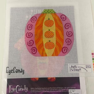 Puede incluir: Un lienzo de punto de aguja con un diseño de calabaza estilizada con secciones rosas, naranjas y amarillas. La calabaza tiene un tallo a cuadros verdes y tres pequeñas calabazas naranjas apiladas verticalmente en el centro. El texto incluye EyeCandy, Ruth Schmuff y design 8201.