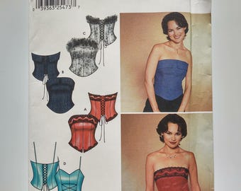 May include: Simplicity sewing pattern 7009. The pattern features corset tops in various colours and styles. The pattern includes illustrations of the finished garments and a photo of a woman wearing a blue strapless top and a red strapless top.