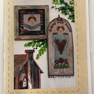 Peut inclure: Un emballage présentant deux articles de décoration intérieure : une applique encadrée et une tenture murale. L'applique encadrée mesure 28 cm et la tenture murale 61 cm. Les deux présentent le texte "Bless Our Home" et un motif de style folk art.