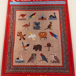 May include: A softcover book titled Quilt a Koala: Australian Animals & Birds in Patchwork by Margaret Rolfe. The cover features a quilt design displaying various fabric-pieced Australian animals and birds on a textured tan background.