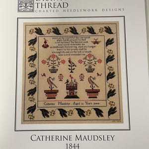 May include: A reproduction sampler from The Drawn Thread Collection, featuring a detailed cross-stitch design. The sampler includes text, floral motifs, birds, and a central building, all framed by a border of leaves. The text reads "Catherine Maudsley Aged 12 Years 1844."