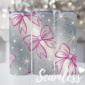 May include: Three silver glitter tumblers with a repeating pattern of pink bows and starbursts. The word "Seamless" is written in white script across the bottom of the tumblers. The tumblers are cylindrical and have a lid.