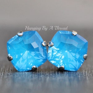 May include: A pair of silver stud earrings with a square, faceted, light blue gemstone.