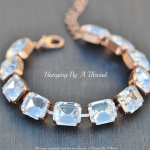 May include: A rose gold bracelet featuring a row of clear square-shaped crystals. The bracelet has a lobster claw clasp.