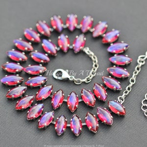 Puede incluir: Un collar de cadena de plata con una doble fila de piedras rojas iridiscentes en forma de marquesa. El collar tiene un cierre de langosta.