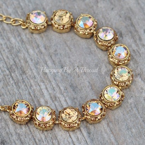 Puede incluir: Pulsera de oro con cadena y cristales redondos iridiscentes. Los cristales están engastados en engastes de oro y tienen un efecto arcoíris.