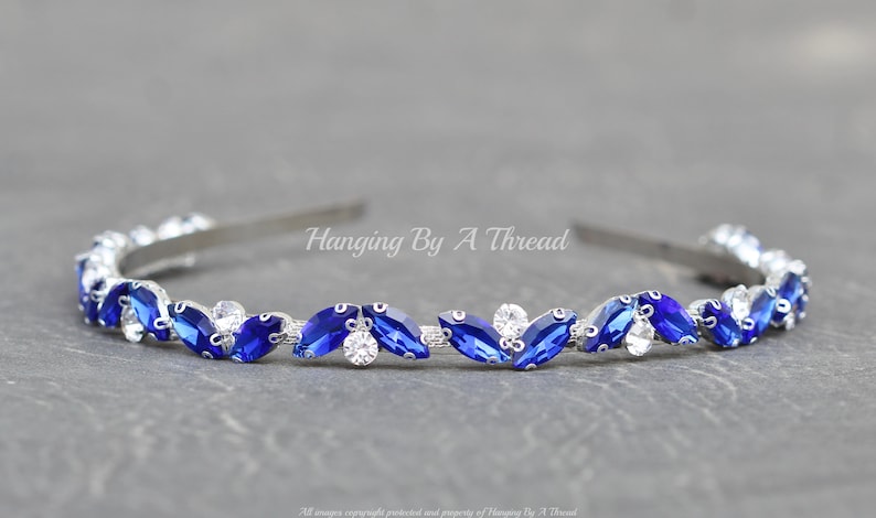 Pu&ograve; includere: Un cerchietto argentato con una fila di strass blu e trasparenti. Il cerchietto &egrave; decorato con un motivo ripetitivo di strass a forma di marquise.