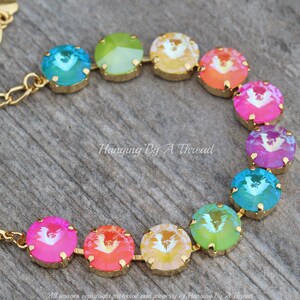 May include: A gold chain bracelet with round, faceted, rainbow-colored crystals. The crystals are arranged in a rainbow pattern, starting with green and ending with pink.