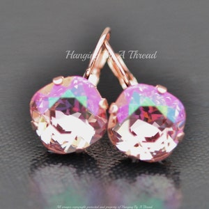 May include: Rose gold earrings with a pink iridescent crystal. The earrings are a simple design with a small crystal and a hook closure.