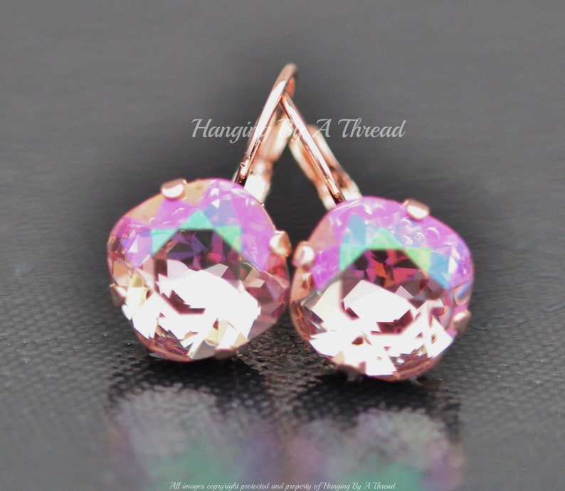 May include: Rose gold earrings with a pink iridescent crystal. The earrings are a simple design with a small crystal and a hook closure.