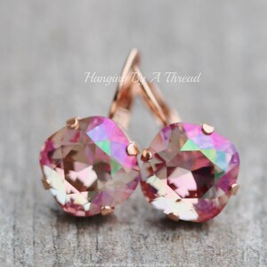 May include: Rose gold dangle earrings with pink iridescent crystal stones. Hanging By A Thread.