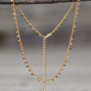 Puede incluir: Un collar de cadena de oro con un delicado colgante y peque&ntilde;os abalorios redondos que cuelgan de la cadena.